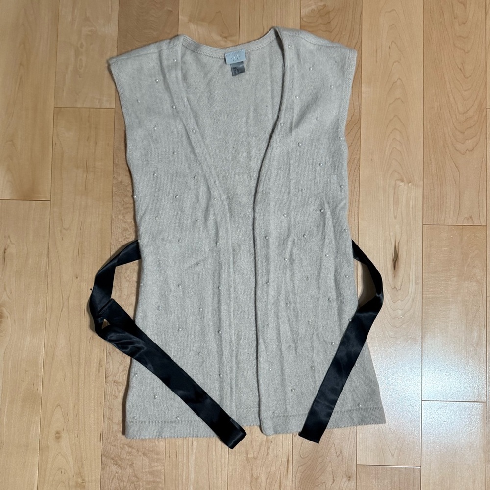 Sweater vest with pearls and black tie.